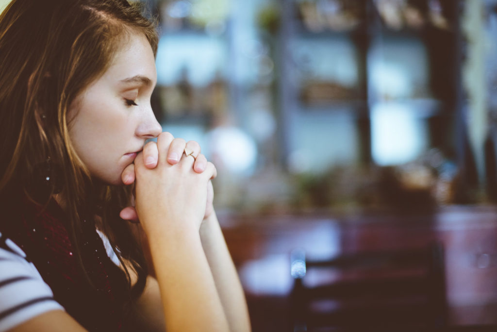 Girl with eyes closed and hands closed in prayer