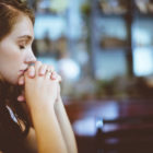 Girl with eyes closed and hands closed in prayer