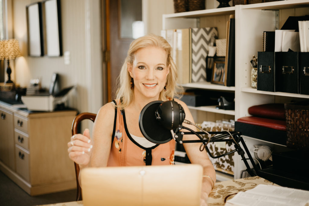 A smiling woman sits in front of a radio microphone