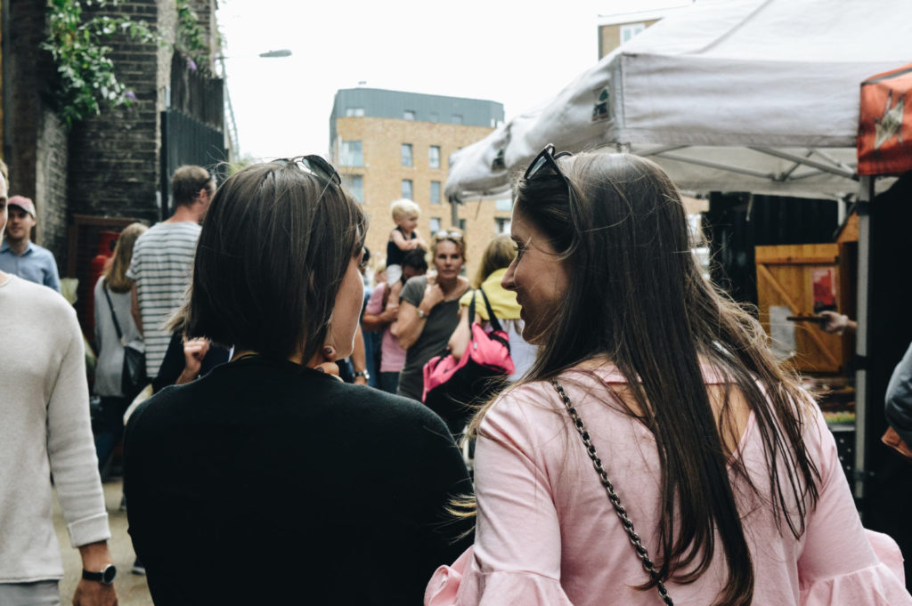 Two women talk while walking down a busy London street