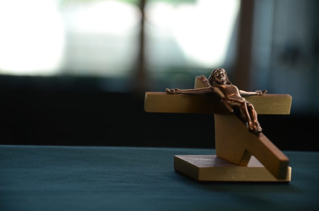 Small wooded figure of Jesus nailed to a cross sits on a table