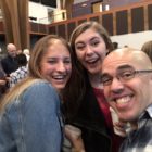Dos universitarias y un cuarentón con gafas y la cabeza rapada posan para un selfie en el santuario de una iglesia