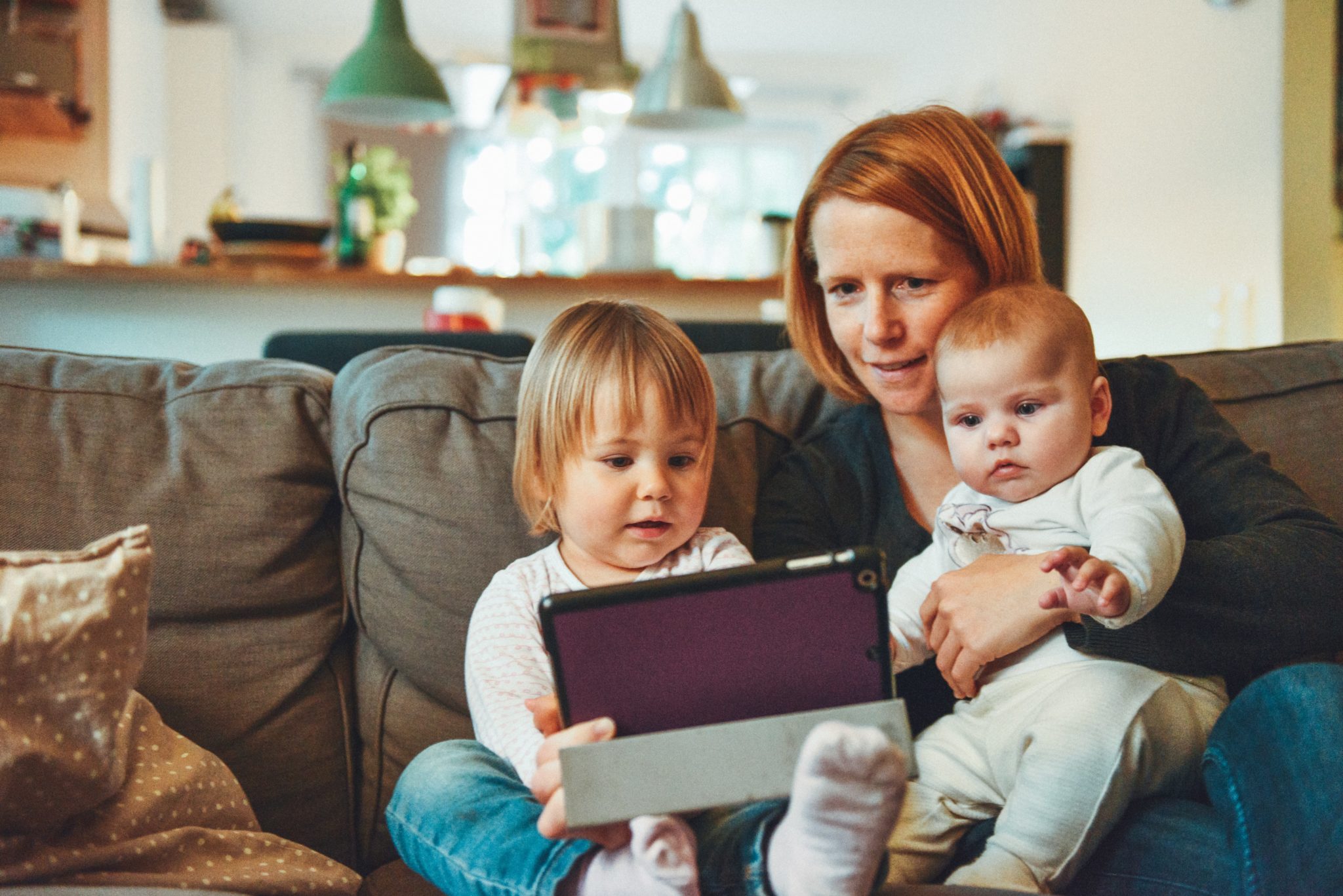 Women with two young kids video chat on a tablet