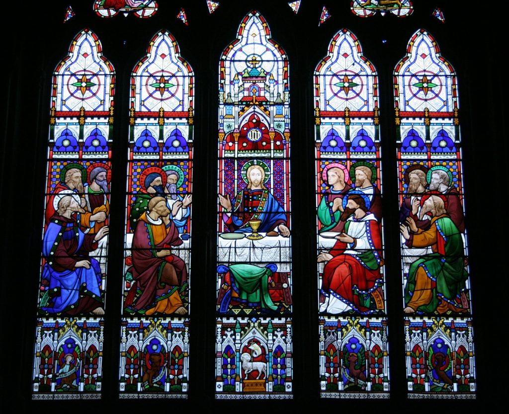 A series of five narrow stained-glass windows portrays Jesus and the disciples at the Last Supper.