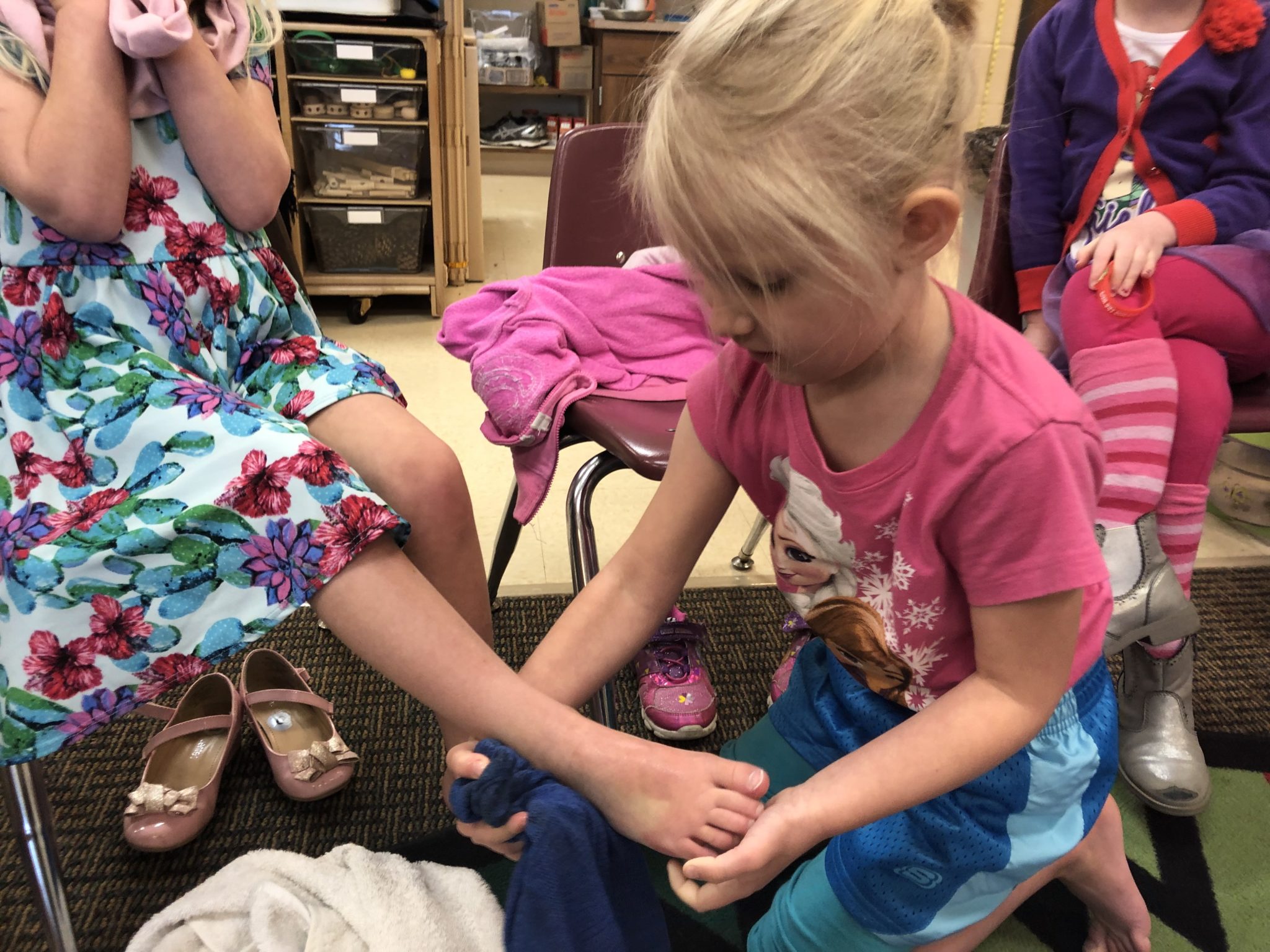 A preschool-age girl washes another girl's foot