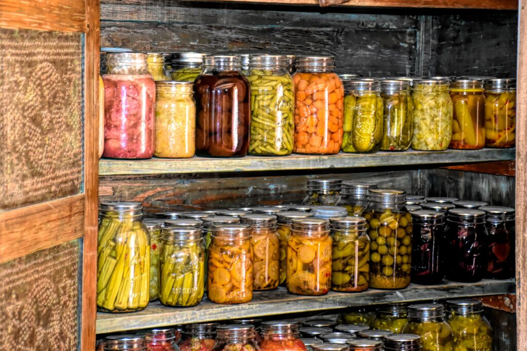 shelves of preserved fruits and vegetables in glass canning jars
