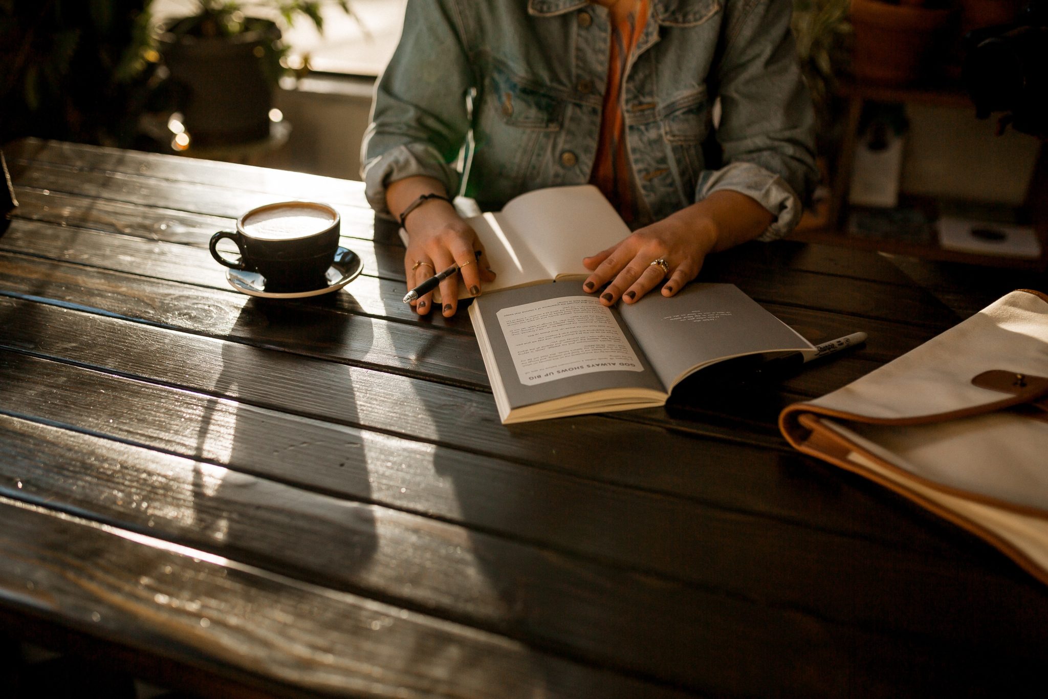 person journaling in a notebook on brown wooden table