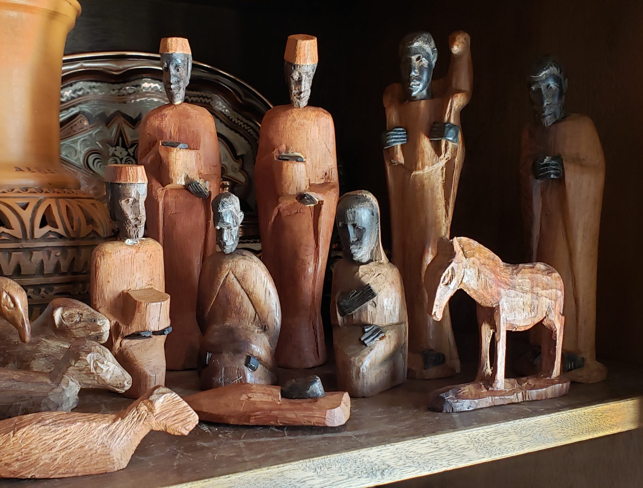 Un belén de madera de estilo africano está expuesto en una estantería.