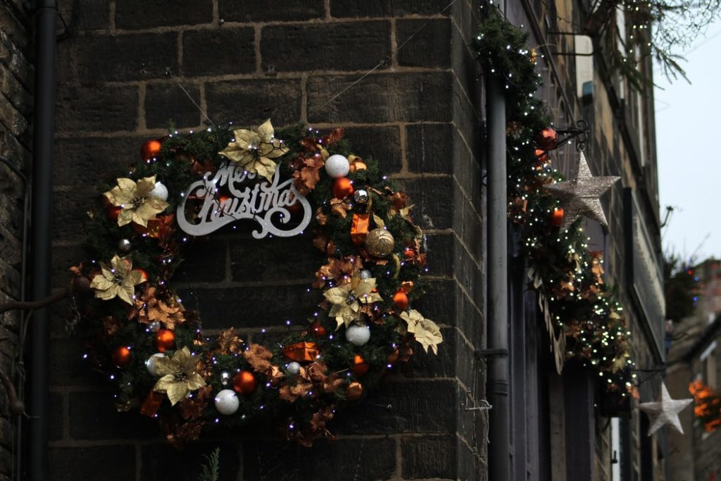 A Christmas wreath hangs on the side of a brick building.