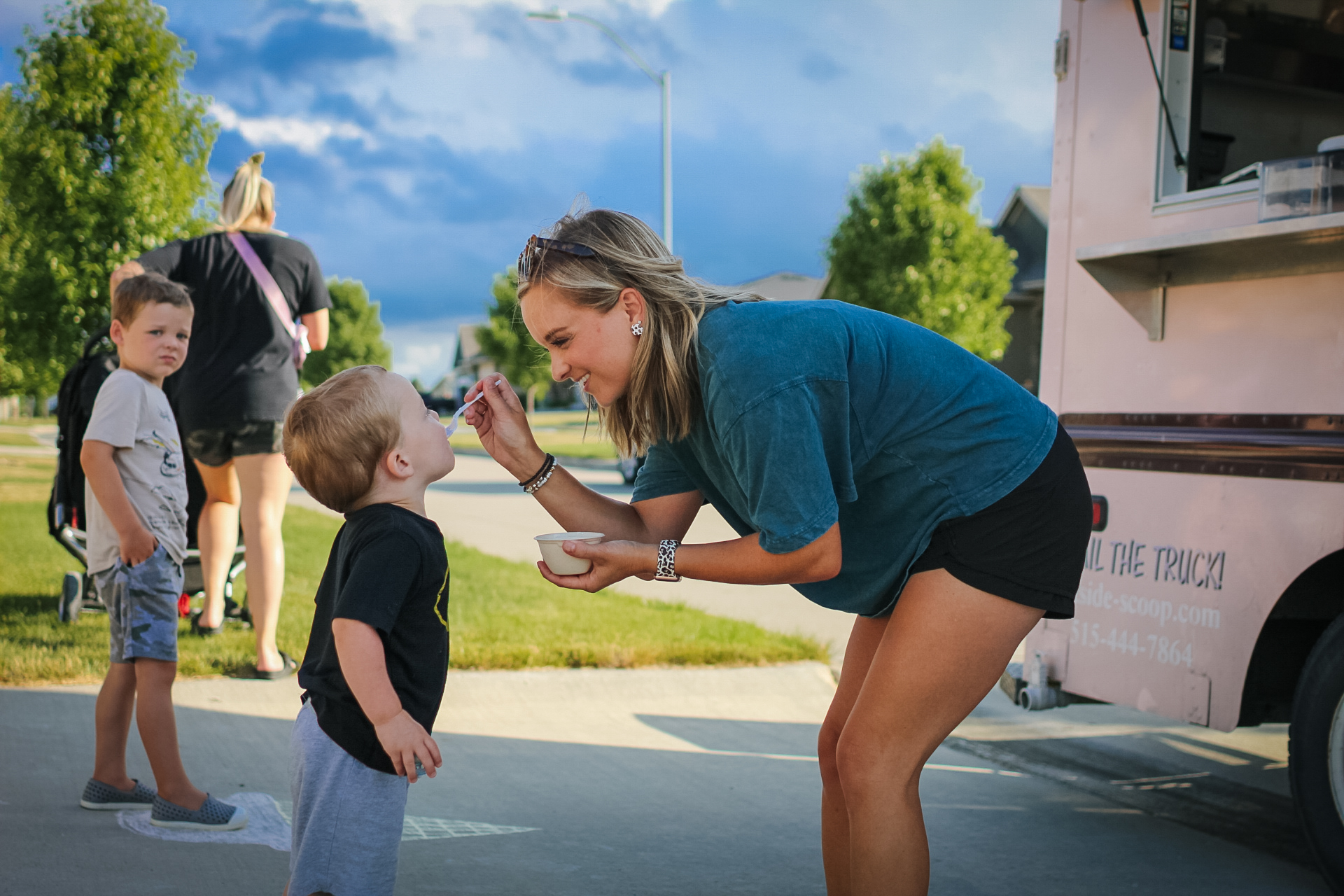 A young woman spoons ice cream into a young boy's mouth.