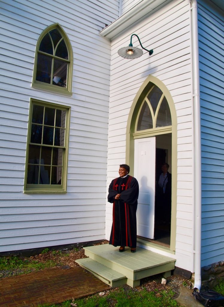 Pastor standing at the entrance to a church to welcome people in