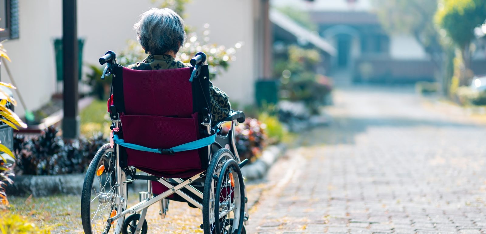 woman sitting on wheelchair facing away from the camera in a residential area.