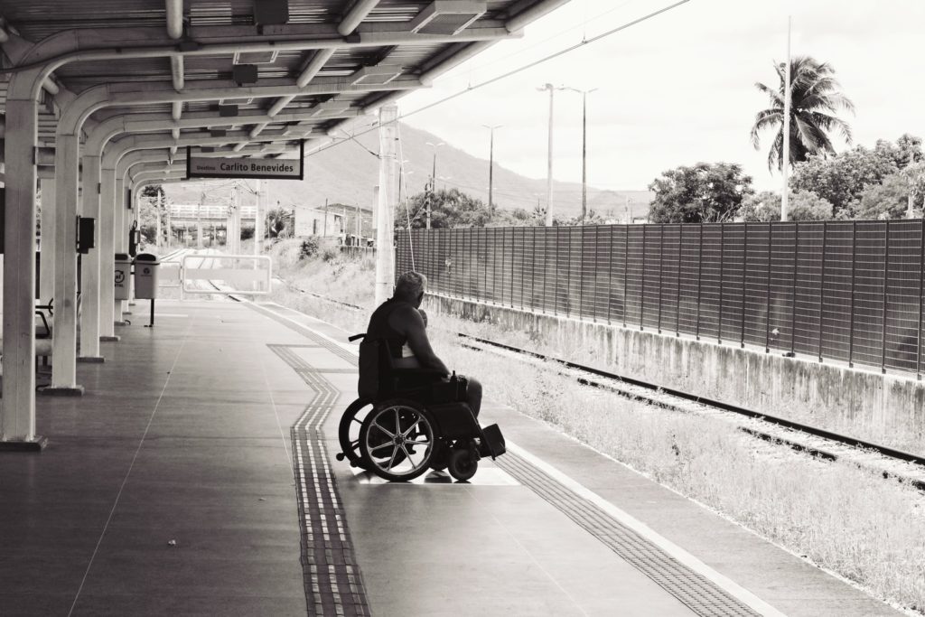 Person in wheelchair at train station on the edge of the platform