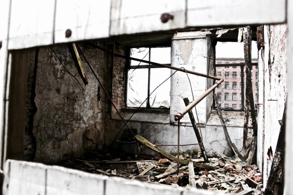 foto en blanco y negro de una ventana reventada y una habitación llena de escombros