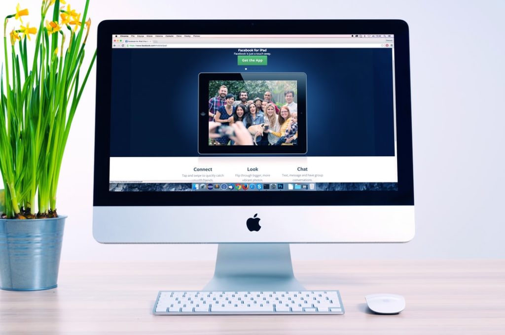 El ordenador de Apple muestra una foto de gente feliz en la página de inicio de un sitio web