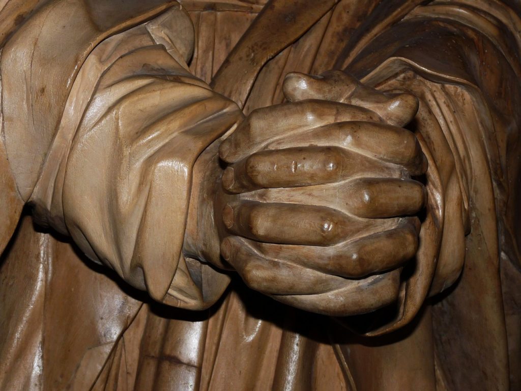 a wood sculpture of folded praying hands