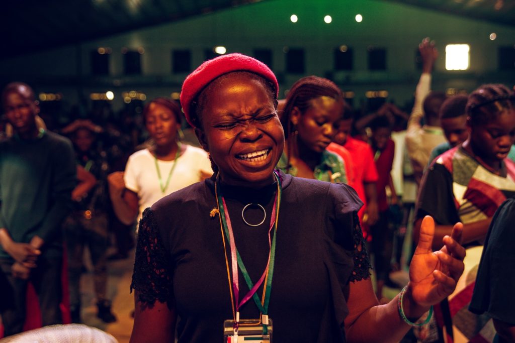 an African woman passionately prays during worship