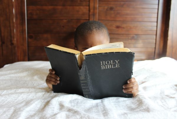 Child reading the Bible while lying on bed