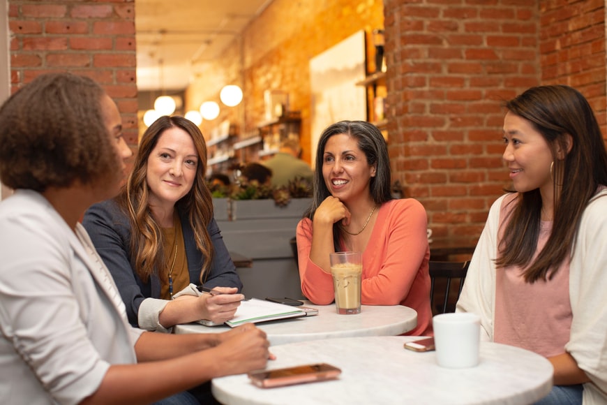 cuatro mujeres de distintas edades hablan en una cafetería