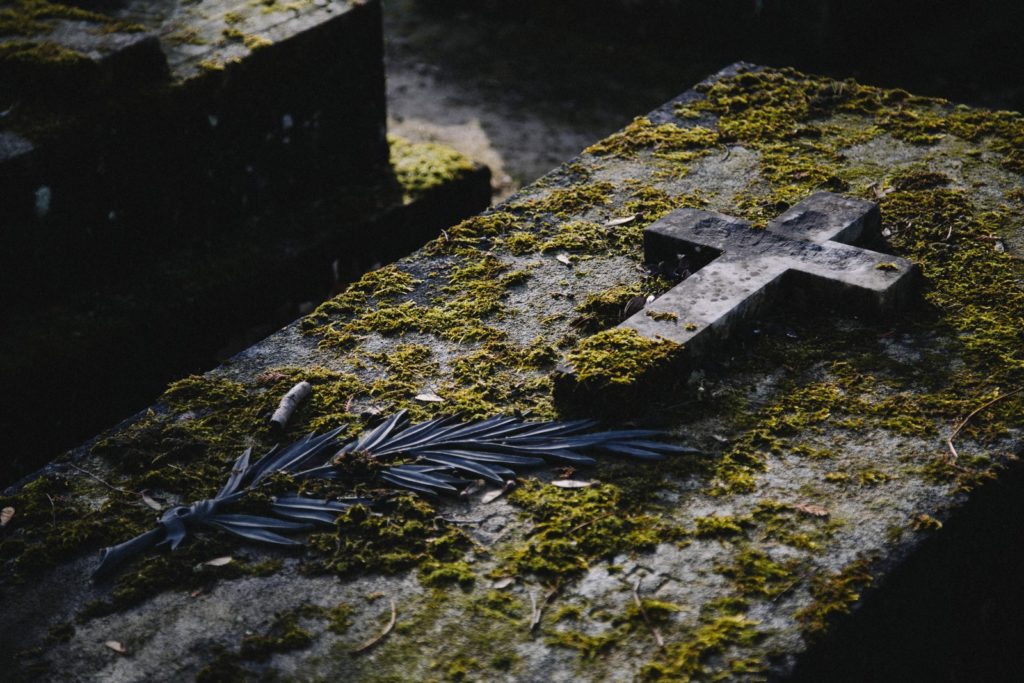 cruz de piedra sobre lápida musgosa