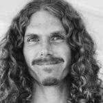 black and white photo of man with long curly hair, mustache, and goatee