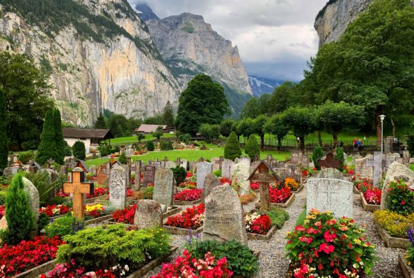 Las lápidas de piedra con flores rojas y los arbustos se encuentran entre montañas en Suiza