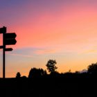 direction sign posts silhouetted by the sunset