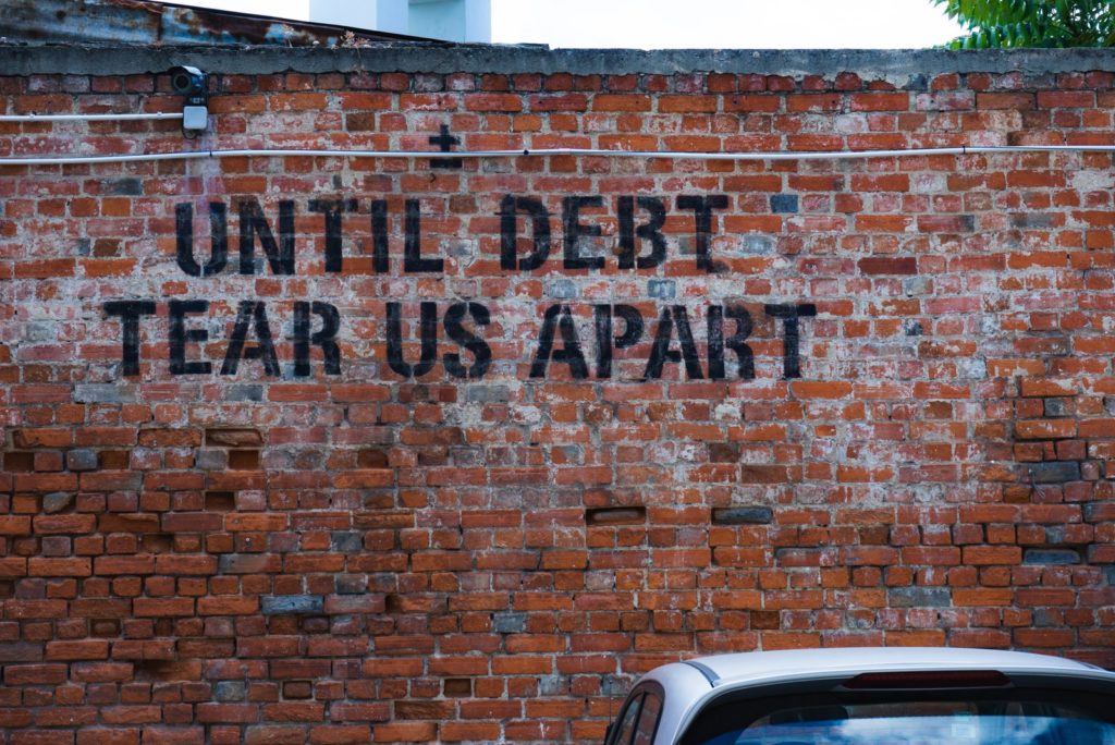 "Until debt tear us apart" written on a brick wall