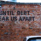 "Hasta que la deuda nos separe" escrito en una pared de ladrillos
