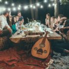 diverse group of friends converse over low wooden table outside
