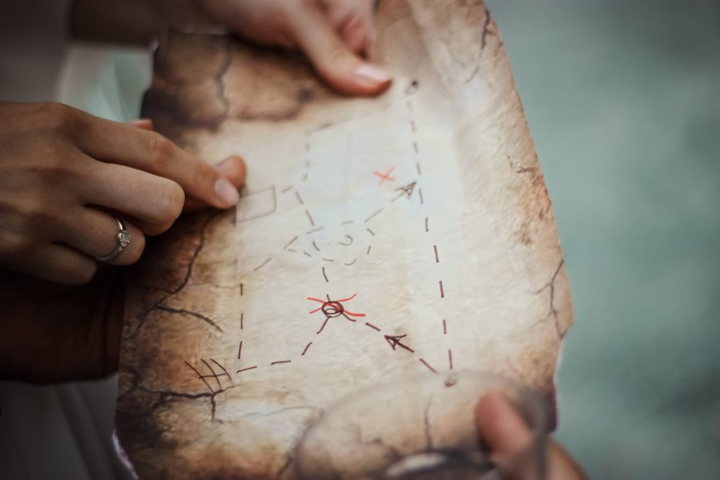 las manos sostienen un mapa desgastado con marcas marrones y rojas
