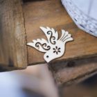 ornate wood cut-out of a dove lays on top of rough wooden table