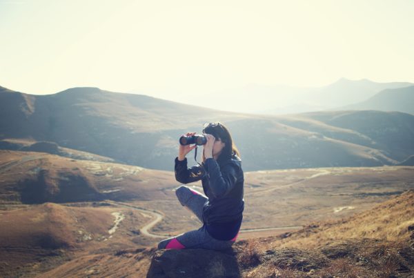 woman with binoculars looks across South African landscape
