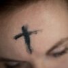 ashes in the shape of a cross on a woman's forehead