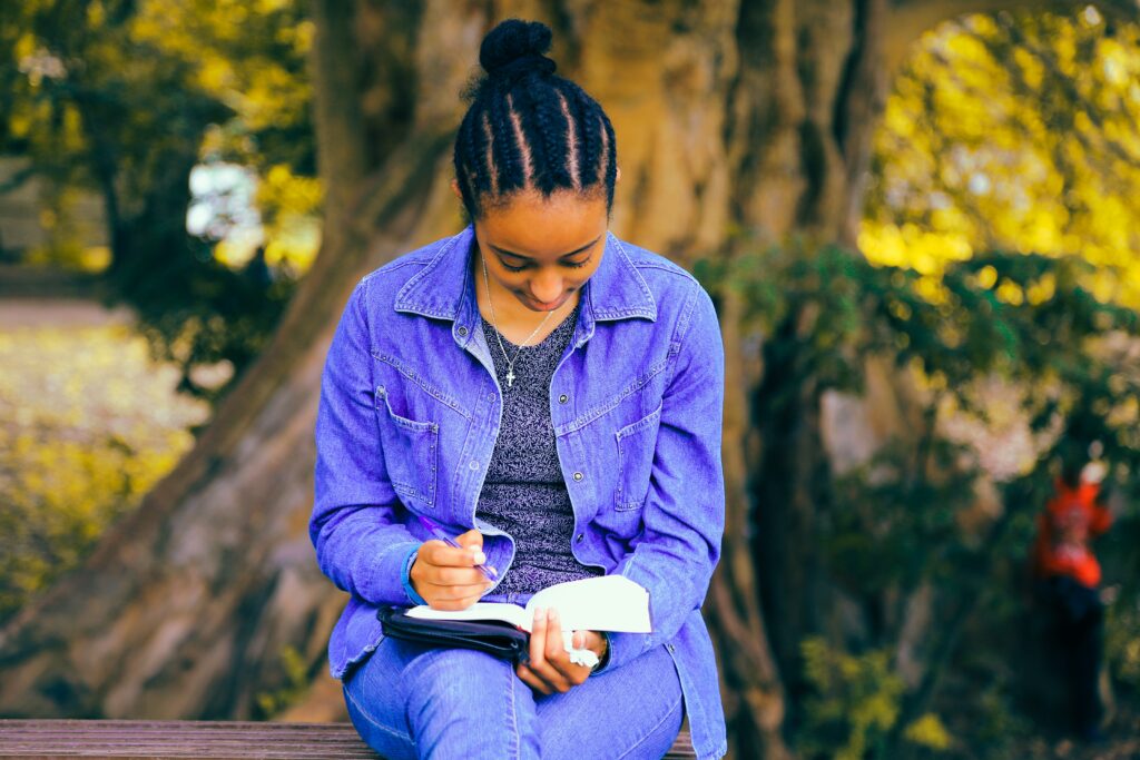 Una joven negra lee la Biblia en un banco al aire libre