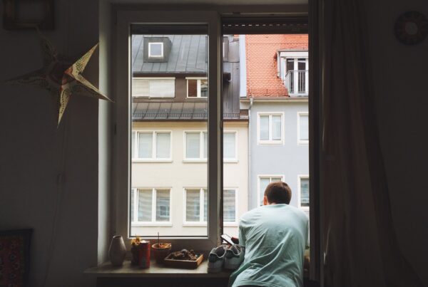 man looks out window at buildings