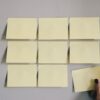 bloque de nueve notas adhesivas amarillas en blanco sobre pared gris