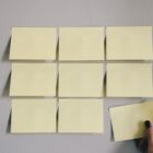 block of nine blank yellow sticky notes on gray wall