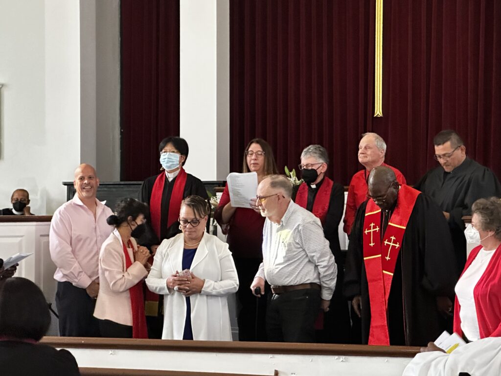 robed church leaders pray over woman being installed as pastor
