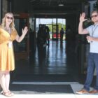 man and woman smile and wave at open church doors