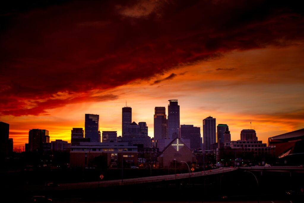 Minneapolis skyline with cross lit up and fiery red-orange clouds above
