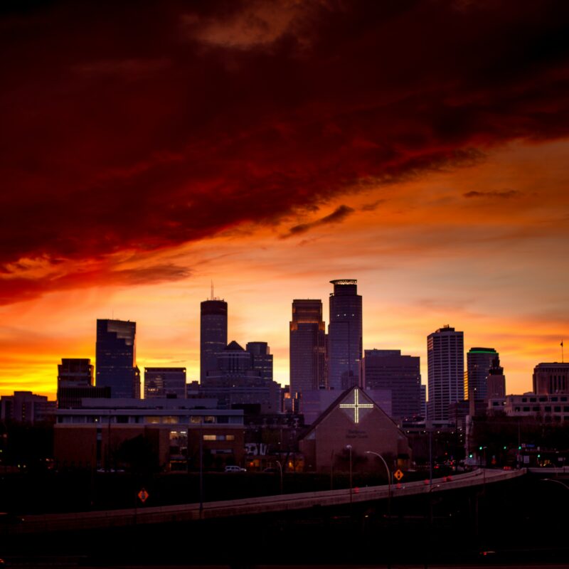 Minneapolis skyline with cross lit up and fiery red-orange clouds above