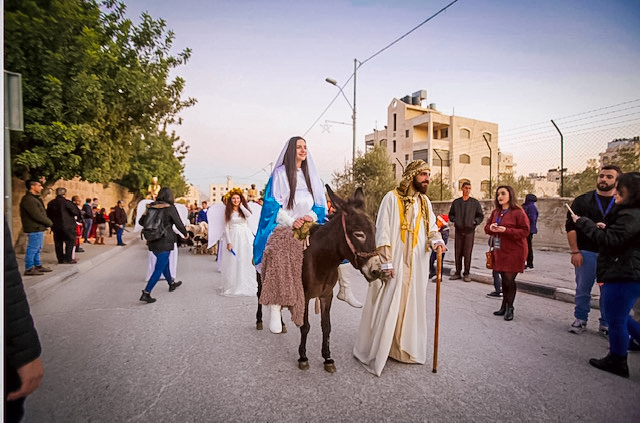 personas vestidas de María y José encabezan el desfile de Navidad en Belén