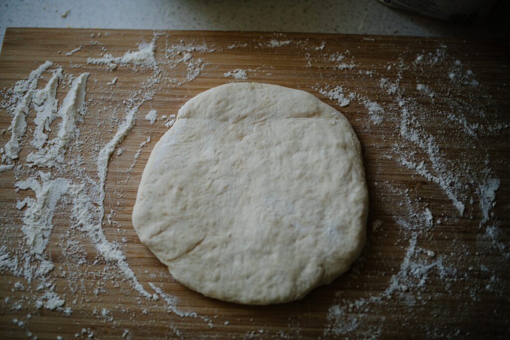 pizza dough on flour covered wood board