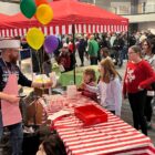 man in hat and apron serves popcorn to kids at a church carnival
