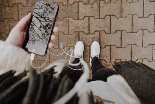 feet on brick pathway with phone and earbuds in hand