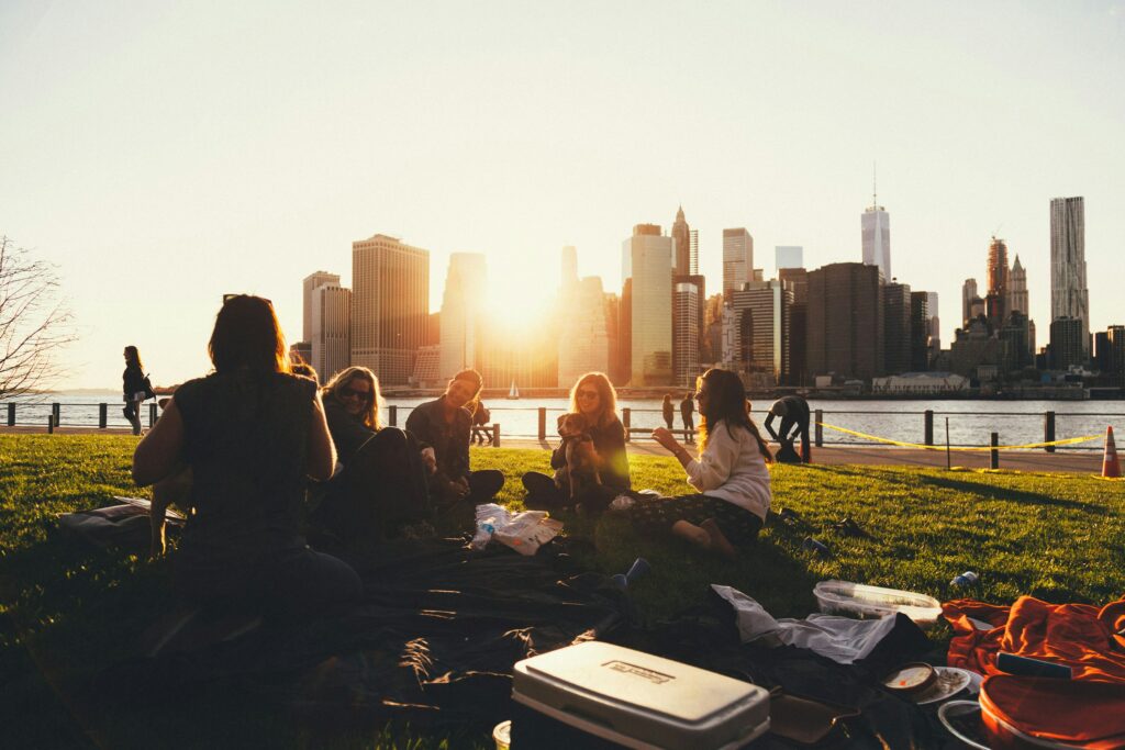 group of five people sit outside and talk with city skyline in background