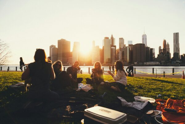 group of five people sit outside and talk with city skyline in background