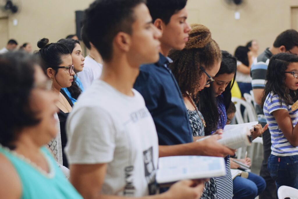 young people stand and look at Bible at church