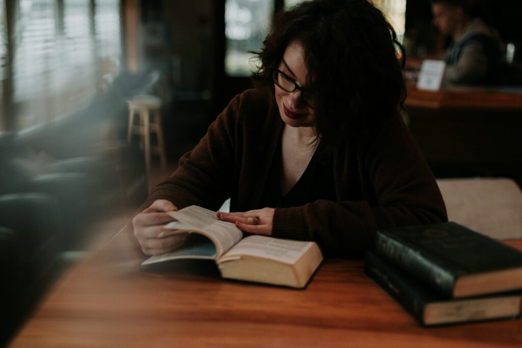 mujer leyendo la Biblia en una mesa con otros libros